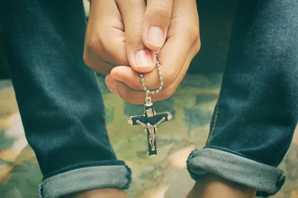 Hands praying with cross