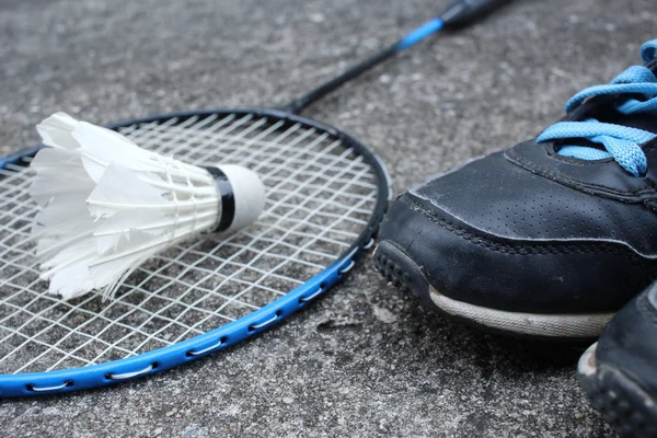 Sport shoes with shuttlecocks and badminton racket.