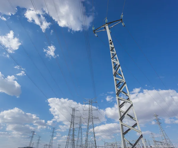 Wide view of electric tower group over blue sky and clouds