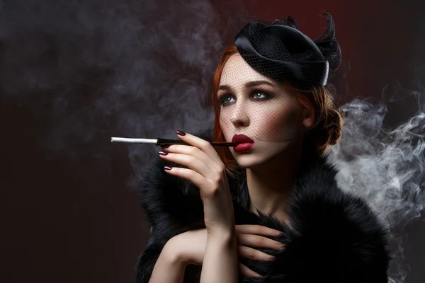 Beautiful girl with smoky eyes and red lips holding cigarette