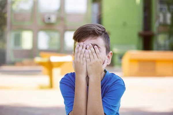 Cute upset boy pouting in the park on a sunny day