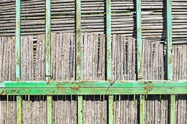 Old rusted metal decorative grate with dry cane fence behind him. Retro style, classical decor, unusual texture.