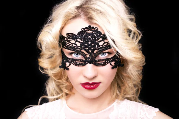 Beautiful fashion model girl with blond hair in mask.Portrait of glamour woman with bright makeup isolated on black background.