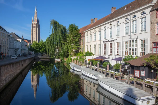 BRUGES, BELGIUM - JUNE 12, 2014: Look to canal from Sint Jan Nepomucenus bridge with the tower of Our Lady church in morning light.