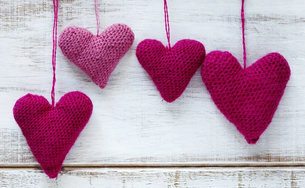 Crochet pink hearts on wooden background