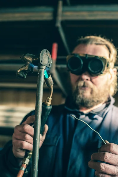 Man with goggles soldering iron pipe