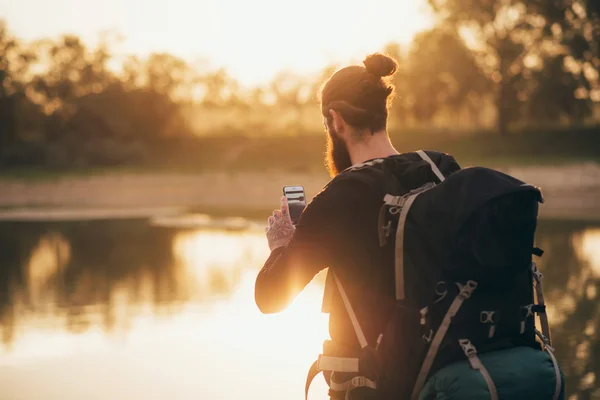 Backpacker photographing landscape with smartphone