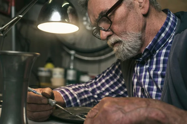 Senior man repairing tin plate