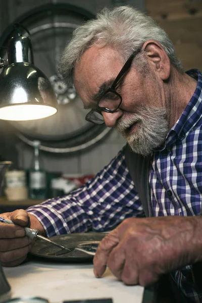 Senior man repairing tin plate