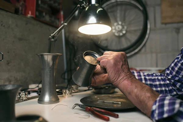 Man inspecting antique tin vase