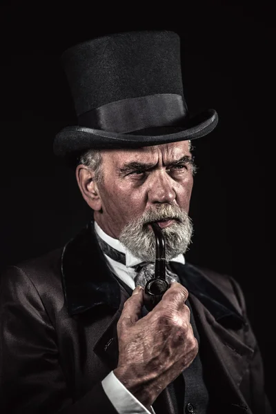 Pipe smoking vintage victorian man with black hat and gray hair