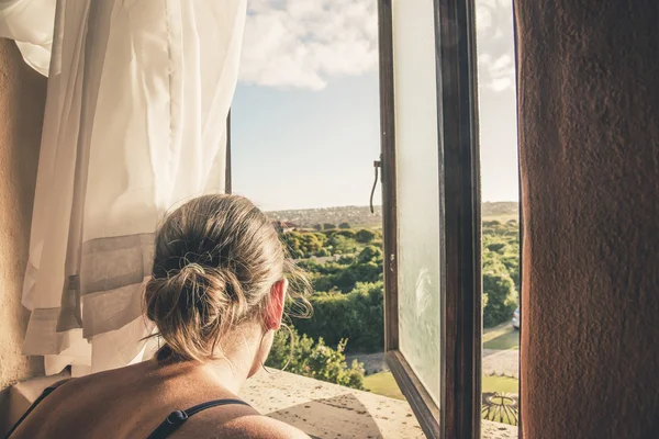 Over the shoulder shot of brunette woman looking through window