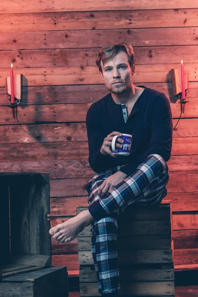 Man with blonde hair and beard wearing winter sleepwear. Sitting