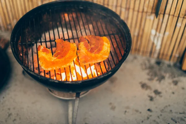 Fresh pumpkin grilling over hot coals on a BBQ