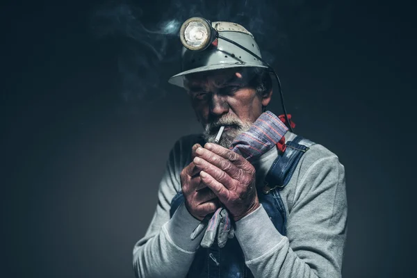 Bearded Miner Lighting his Cigarette on his Mouth