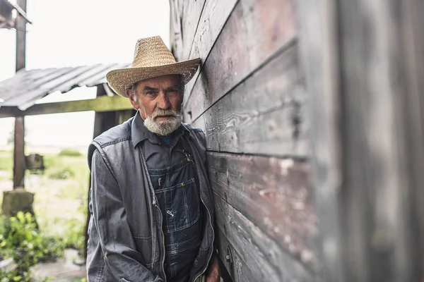 Farmer Leaning Against Farmhouse Wall