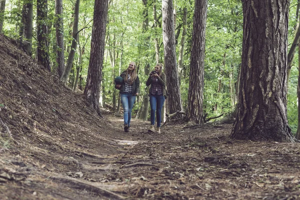 Twin sister walking on forest trail.