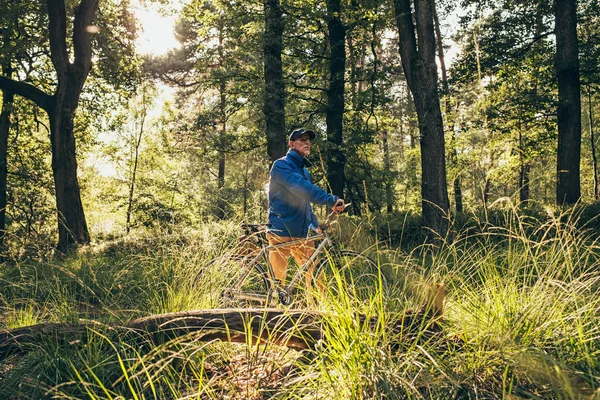 Man standing in forest with bicycle.