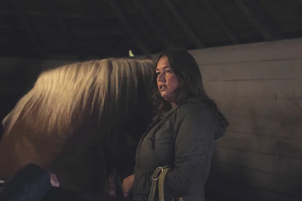 Woman with horse in stable.