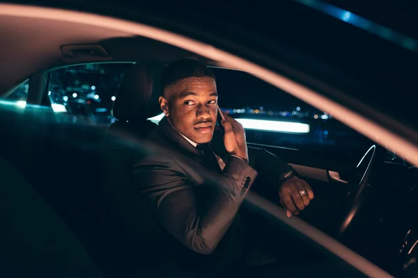 Man in car at night calling with smartphone.