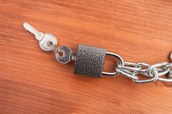 Metal chain links and lock on wooden background