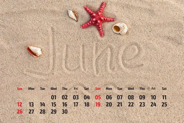 Photo calendar with starfish and seashells on sand beach. June