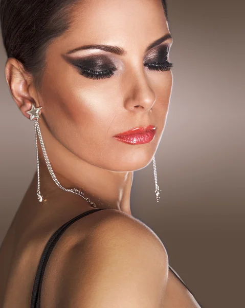 Elegant woman wearing smokey eyes makeup, with eyes closed.