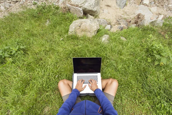 Man working in nature on his laptop over green grass