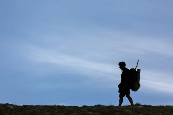 Silhouette of climbing young adult at the top of summit with aer