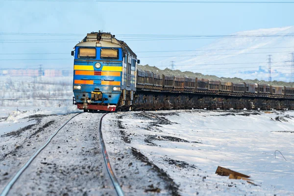 Freight train moving on snow-covered tracks.