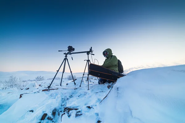 Man with photo camera on tripod taking timelapse photos in the arctic tundra.