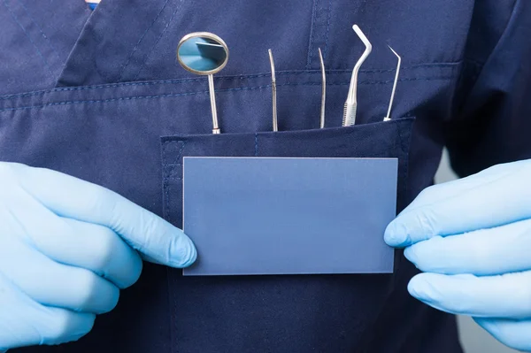 Closeup of dental tools and blue card in dentist hands