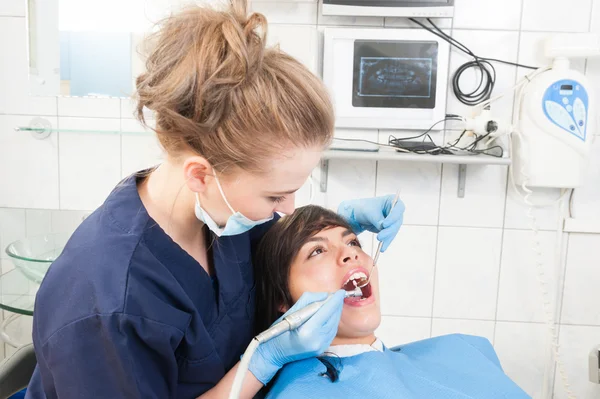 Female patient with open mouth receives dental treatment