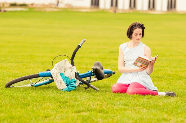 Young hipster female reading a book outside in the park