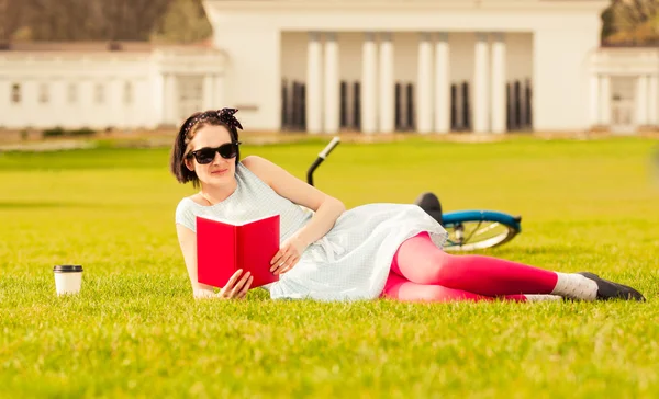 Relaxed woman standing outside and reading in the city park