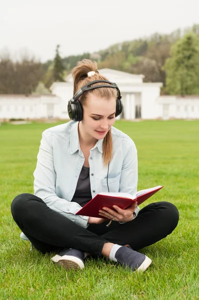 Portrait of joyful female reading a book while listening music