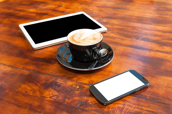 Wooden table with tablet smartphone and coffee cup