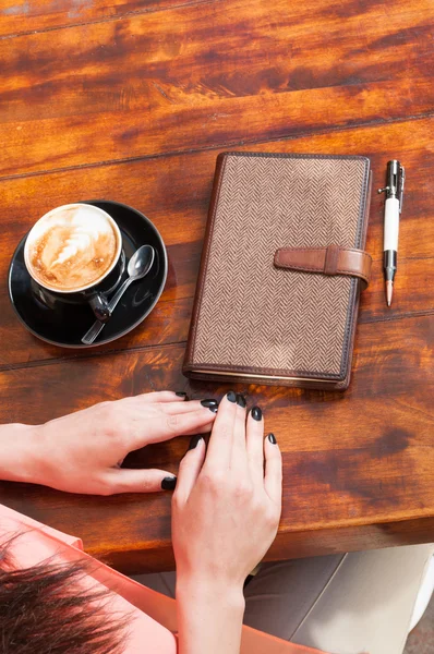 Woman sitting with coffee and agenda on terrace table