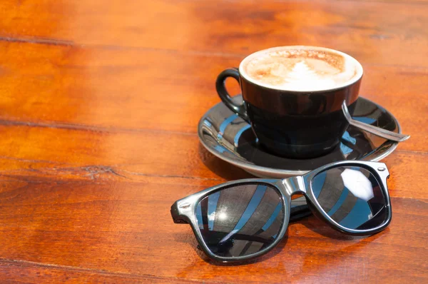 Sun glasses and coffee outside on wooden table