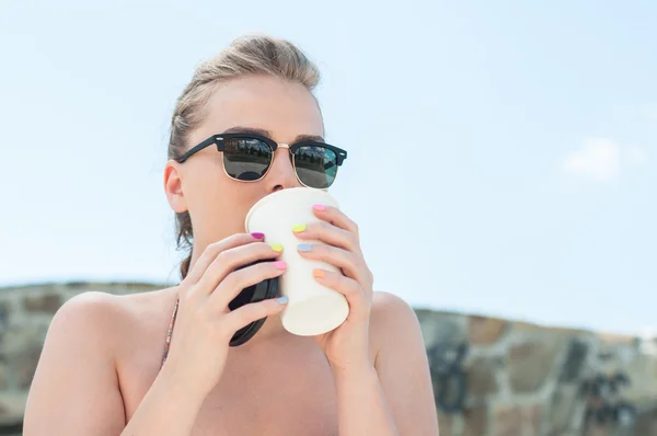 Girl sipping coffee from takeaway cup outside