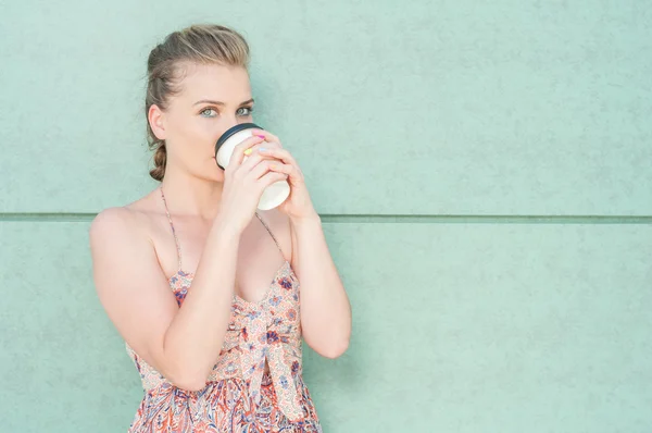 Pretty girl drinking from takeaway coffee cup