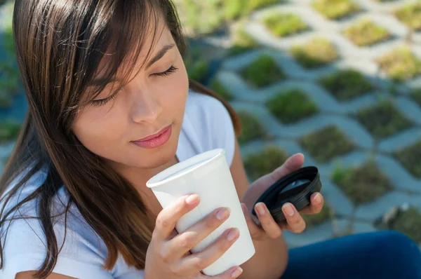 Lady enjoying smell of fresh coffee outside