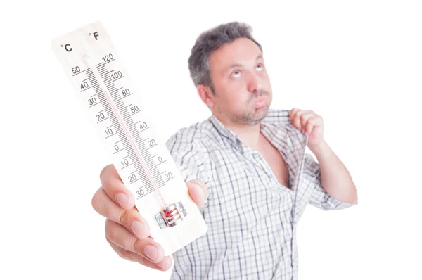Sweaty man holding thermometer as summer heat concept