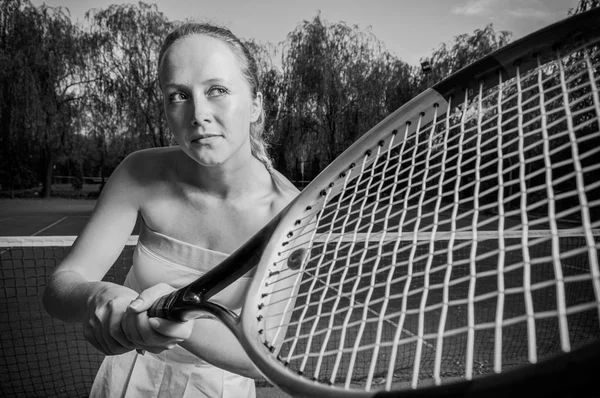 Female tennis player holding racket in black and white image