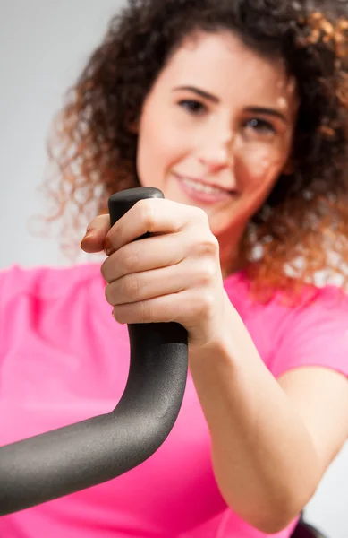 Beautiful female smiling and holding a stationary bike handle