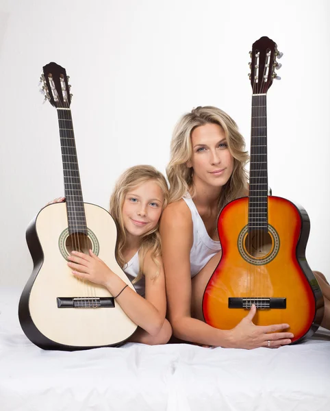 Beautiful blonde mother and her daughter with guitars