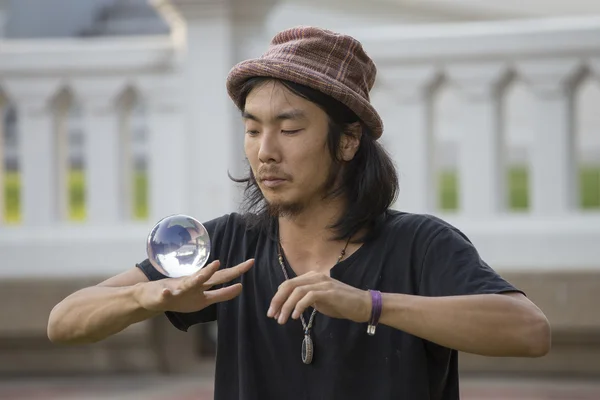 Street performer juggling glass bowl in front of passers-by on the street Khao San Road . Bangkok, Thailand