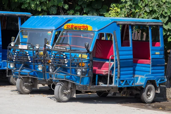 Auto rickshaw taxis on a road. These iconic taxis have recently been fitted with CNG powered engines in an effort to reduce pollution