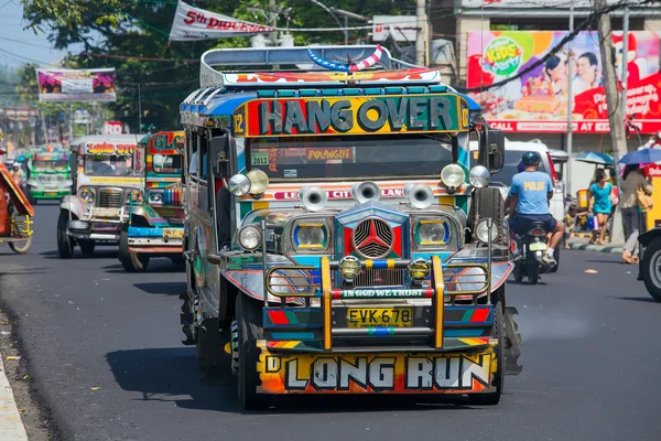 Jeepneys passing, Filipino inexpensive bus service. Jeepneys are the most popular means of public transportation in the Philippines.