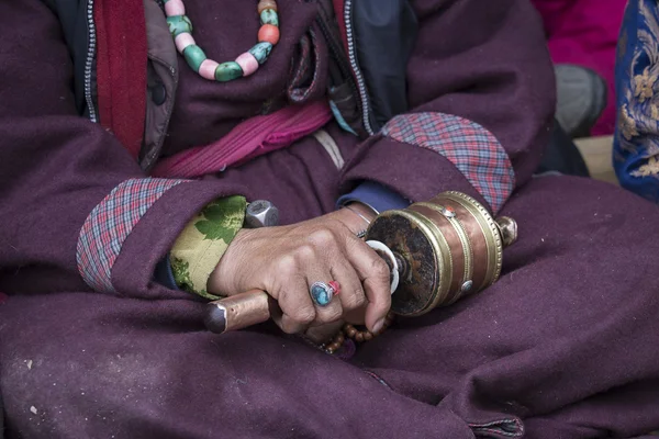 Old Tibetan woman holding buddhist prayer wheel in Lamayuru Gompa, , Ladakh, India.